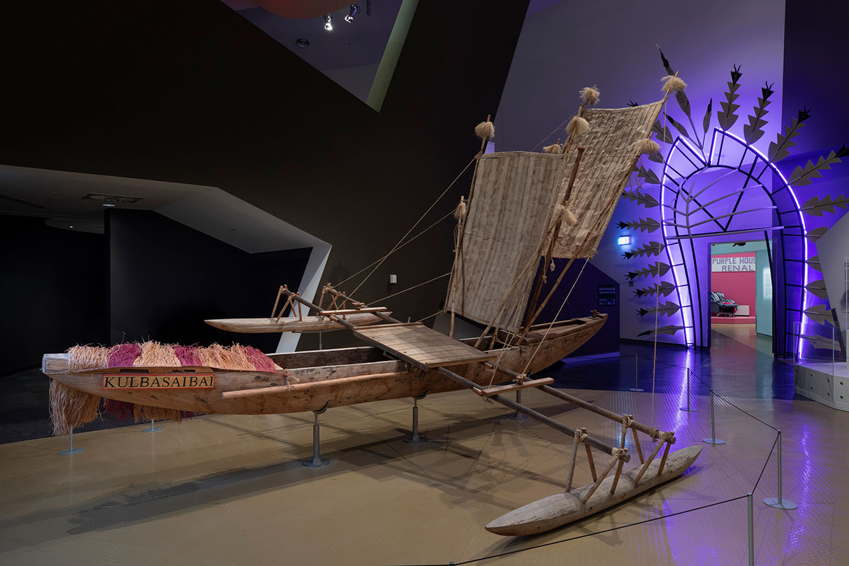 An outrigger canoe on display in a museum gallery.