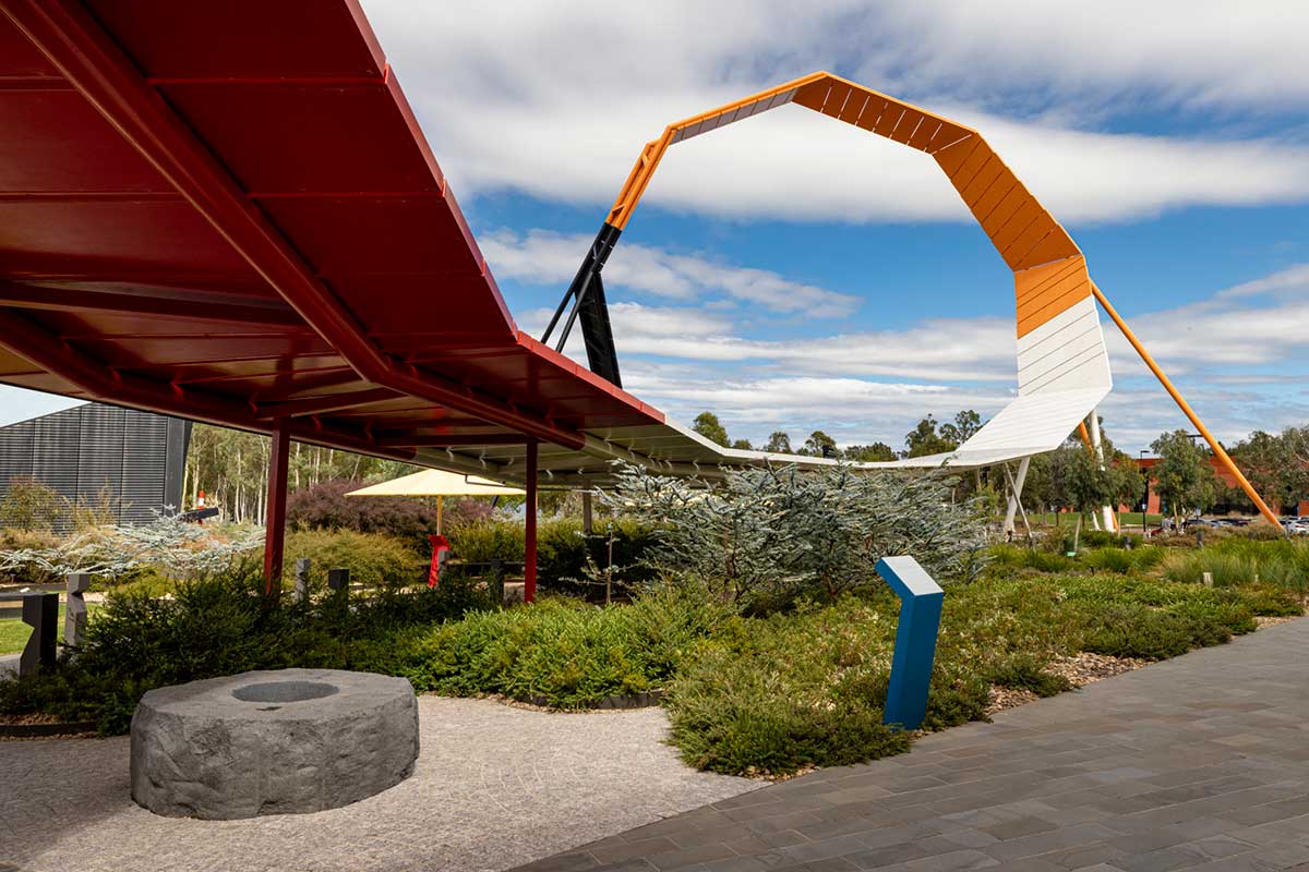 Contemporary sculpture curving above well-maintained gardens and pathways.