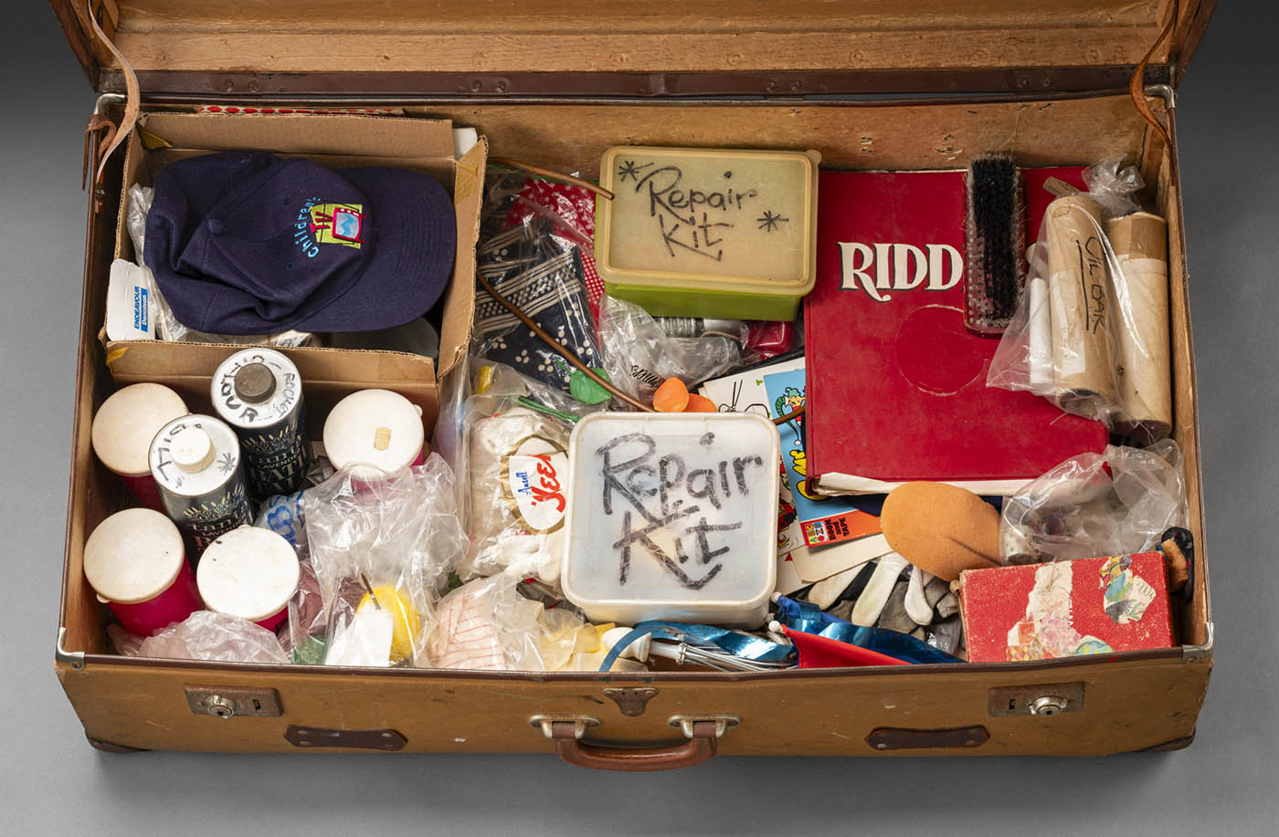 A photograph of Norman Hetherington’s suitcase which he took to the studio when recording. The suitcase is brown with a leather handle and two lockable metal latches.
