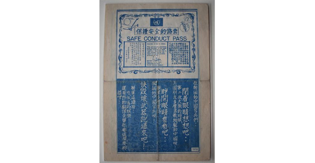 A machine printed leaflet in blue ink on paper. The imagery is divided into two halves. The top half consists of a decorative border within which appears the UN logo flanked by a peace dove and an erhu or Chinese violin.  A row of Chinese characters sits above the words SAFE CONDUCT PASS and below that three columns on different text. The central column reads: SOLDIERS OF THE UN FORCES: This certificate guarantees good transport to any enemy soldier desiring to cease fighting. Take this man to your nearest officer and treat him as an honourable prisoner of war. It is signed MATTHEW B. RIDGWAY General, US Army, Commander in Chief, United Nations Command. 