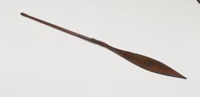 Wooden paddle of a war canoe. The shaft is decorated with ornaments at the handle and at the connection of the blade.