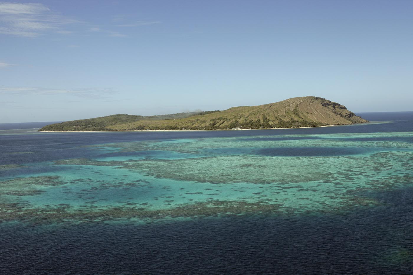 Aerial photo of a small island with reef in foreground.