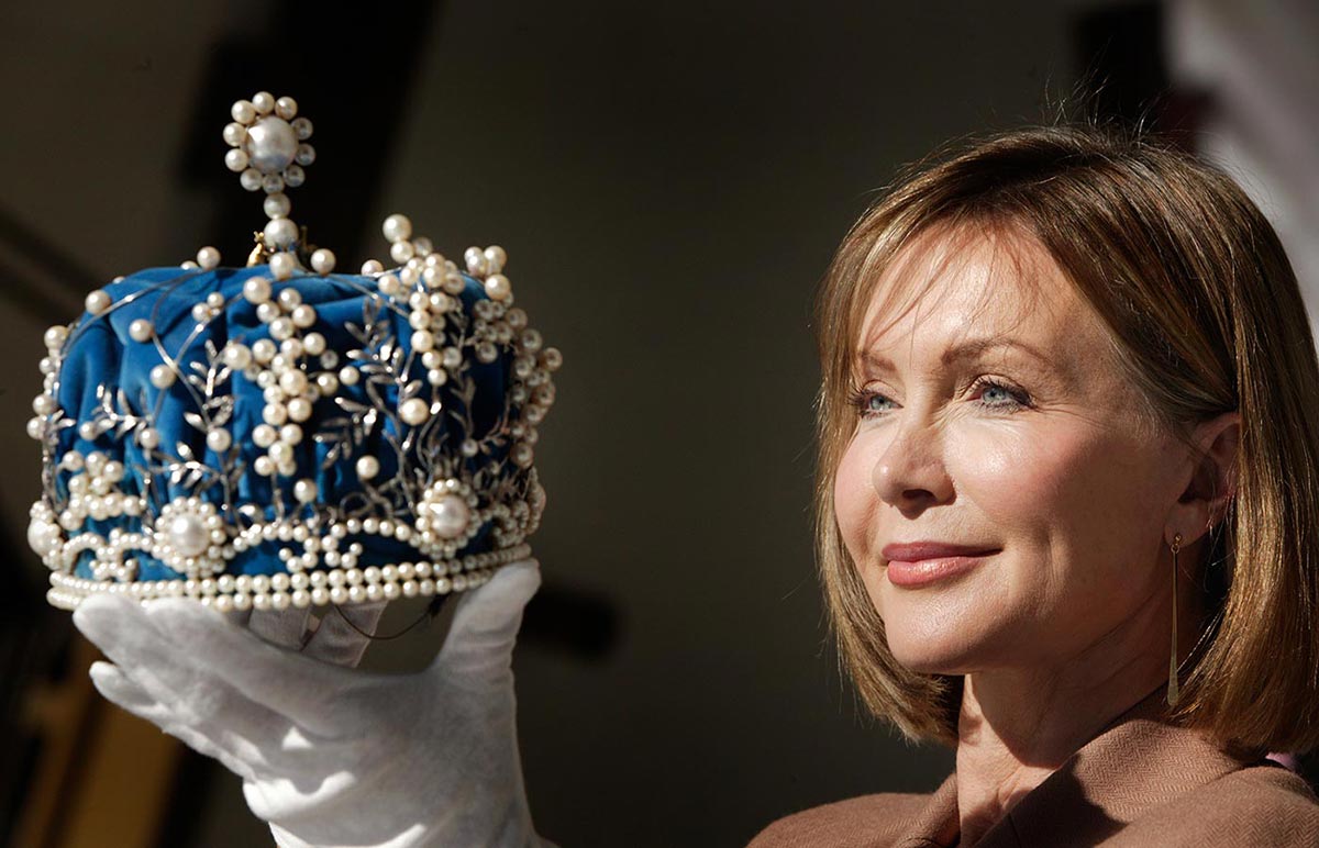 Colour photograph of a woman holding up a crown. - click to view larger image