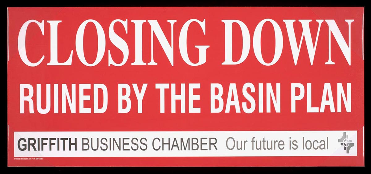 Colour photograph of a sign, printed in white on a red background, which reads: 'CLOSING DOWN, RUINED BY THE BASIN PLAN. Griffith Business Chamber. Our future is local'.