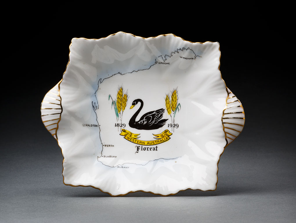 Ceramic plate with gold trim and an illustration of a black swan on a map of Western Australia