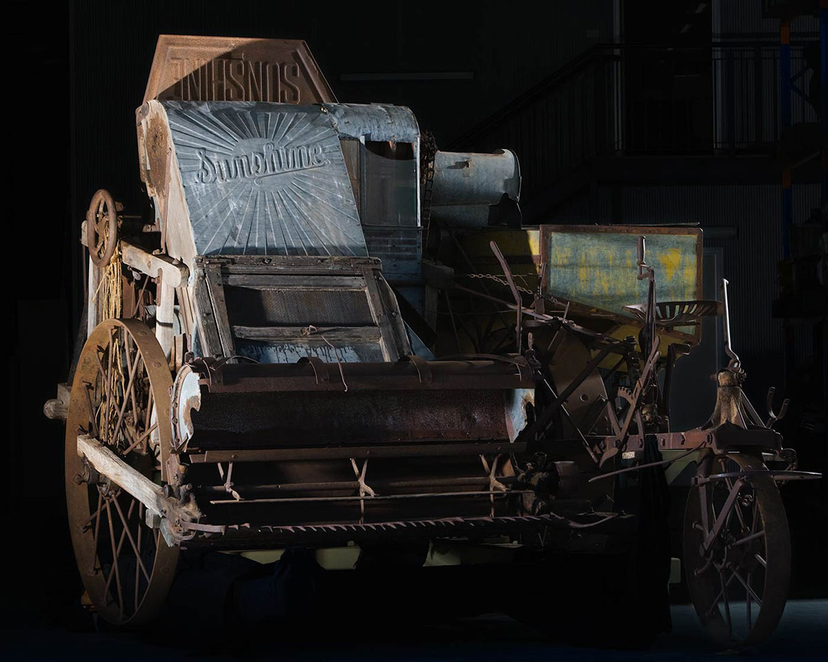 A stripper harvester with the word 'Sunshine' pressed into a sheet of metal at the top of the machine - click to view larger image