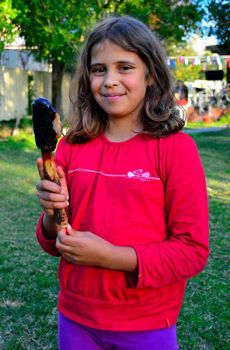 Young girl in a red shirt holding a kodj (axe). - click to view larger image
