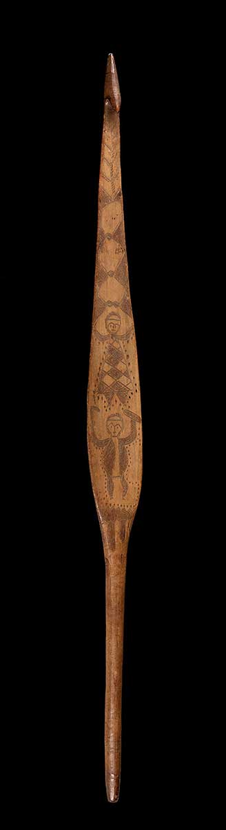 Wooden artefact decorated with complex incised figurative designs, including two human figures. - click to view larger image