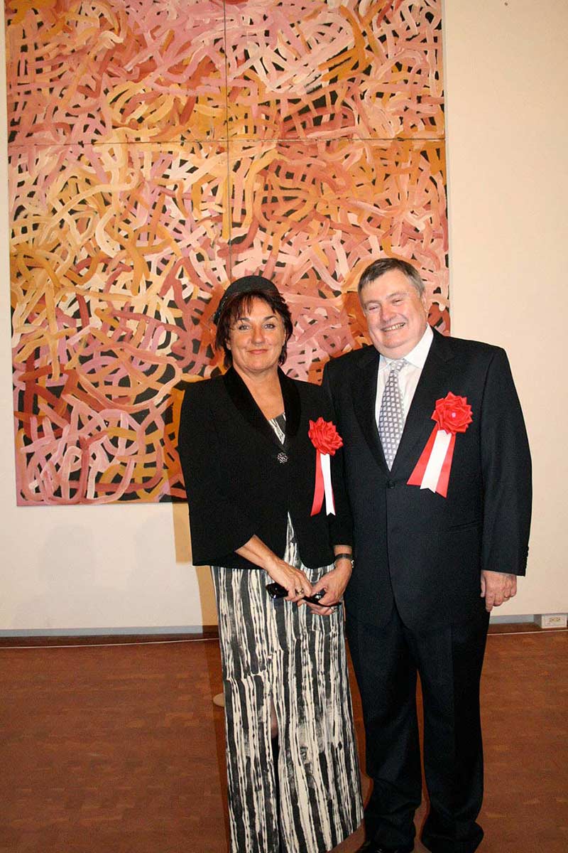 A man and a woman in formal wear standing in front of a large painting. - click to view larger image