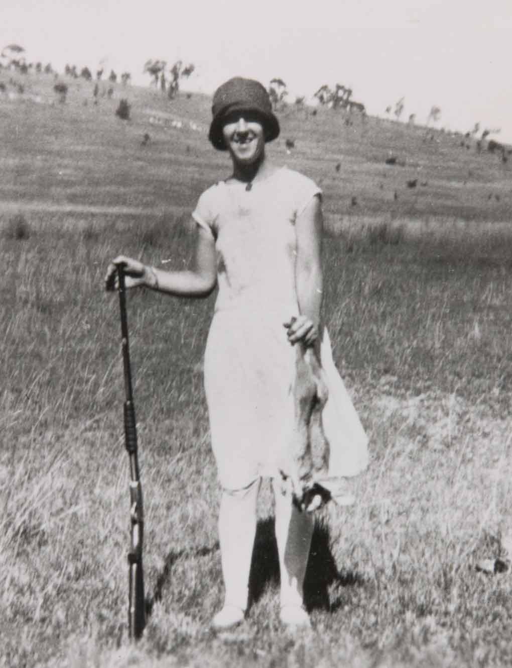 Photograph of a lady at Bathurst NSW in the 1920s with a gun in her right hand and holding a dead rabbit in her left - click to view larger image
