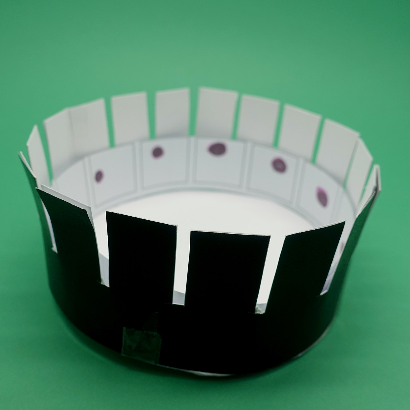 Model of a zoetrope, showing a series of dots drawn on the inside.