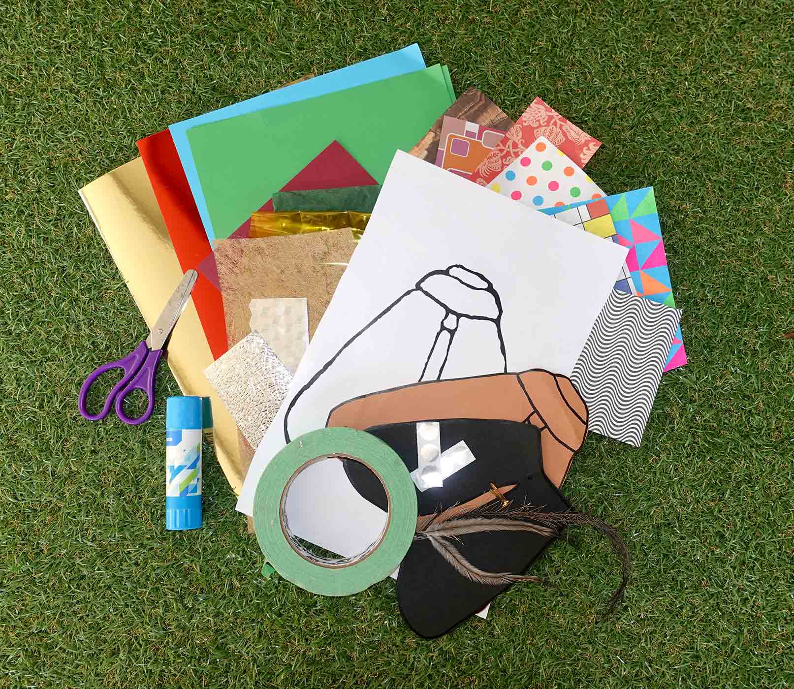 Colour photo of various materials including a paper moth template, scissors, glue, tape, feathers and other materials.