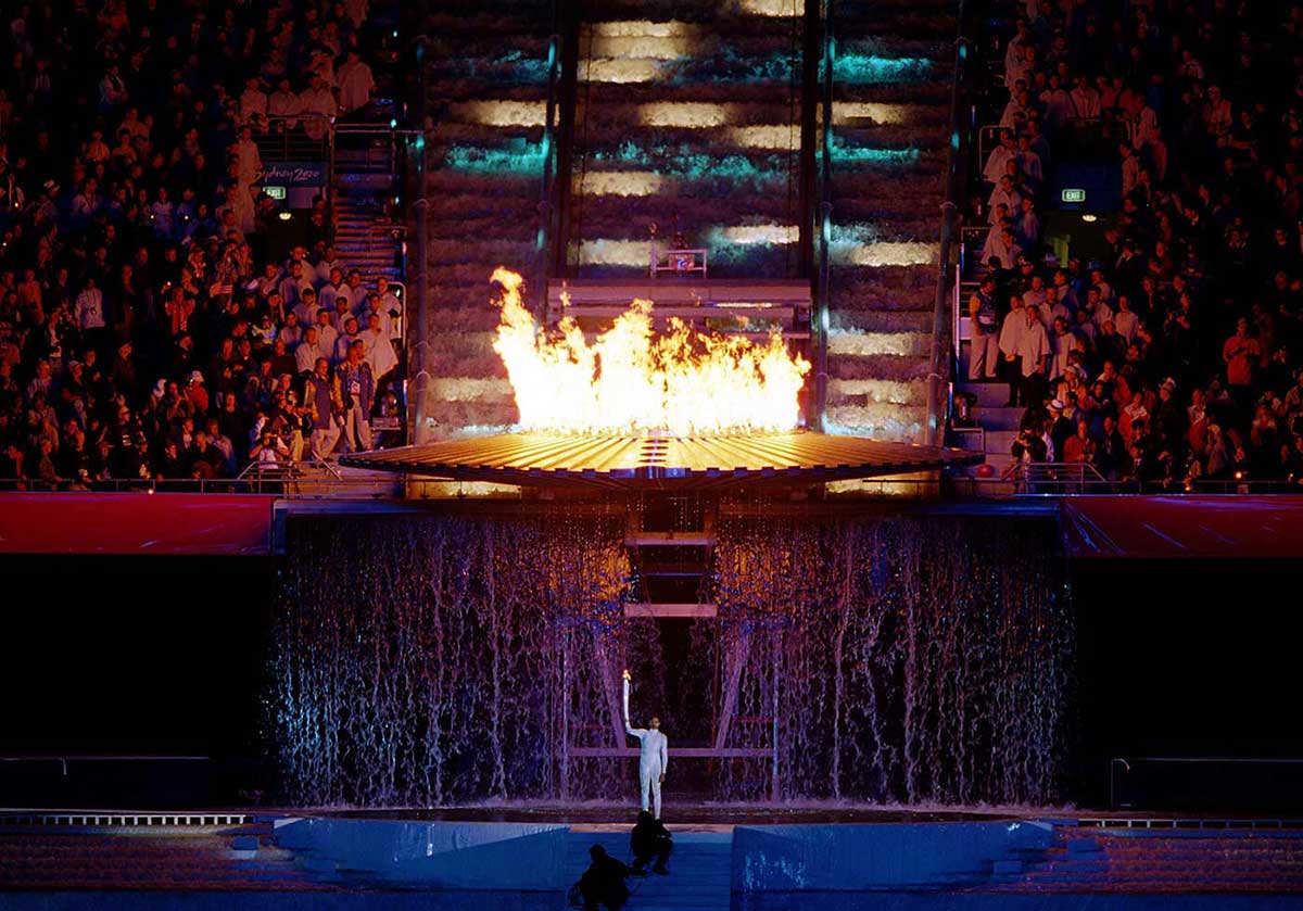 Panorama shot of Cathy Freeman lighting the flame at the 2000 Olympics in front of a large crowd.