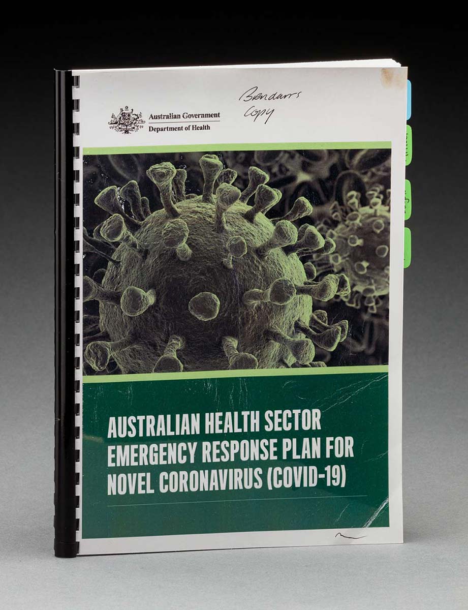 An A4-sized booklet with plastic binding features a front cover with the logo for the Australian Government Department of Health and the text: ‘AUSTRALIAN HEALTH SECTOR / EMERGENCY RESPONSE PLAN FOR NOVEL CORONAVIRUS (COVID-19)’. Handwritten at the top is the text: ‘Brendan’s copy’.