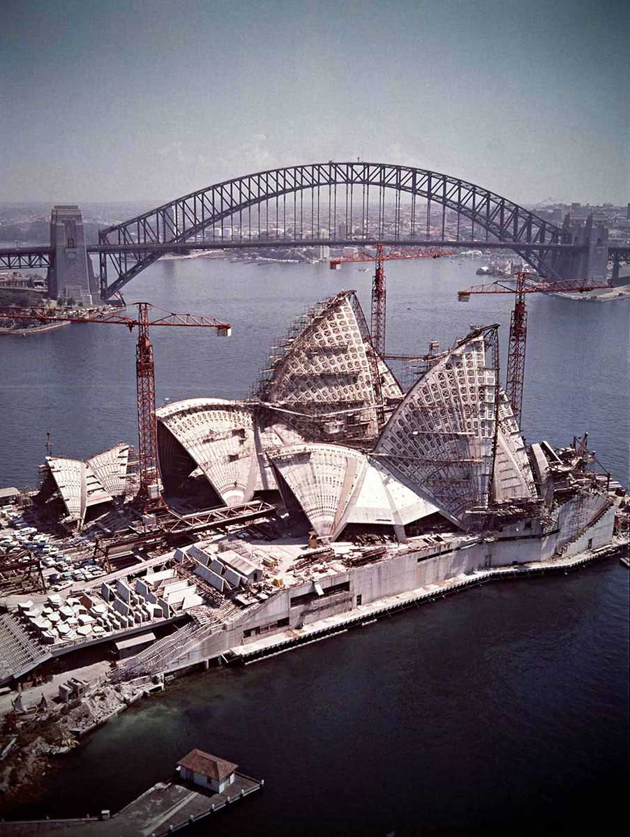 The almost completed Opera House in foreground surrounded by cranes, with Harbour Bridge in background. - click to view larger image