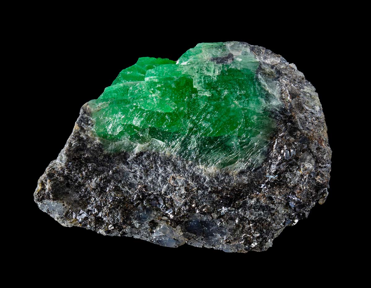 A mineral specimen featuring bright green crystals forming off a base of black quartz. - click to view larger image