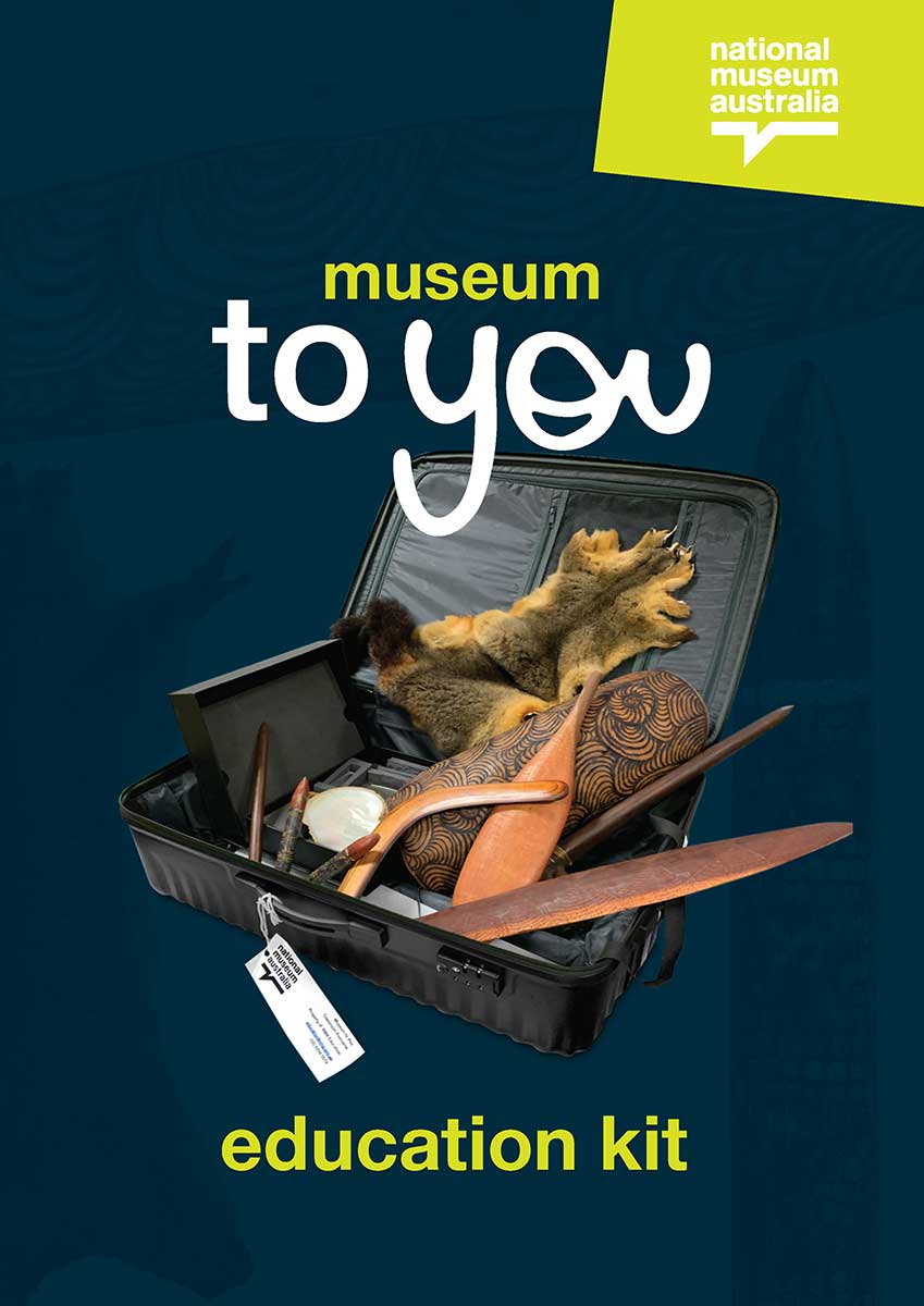 Promotional image of a suitcase with a National Museum of Australia tag containing various objects including clapping sticks, a decorated shield and an animal pelt.