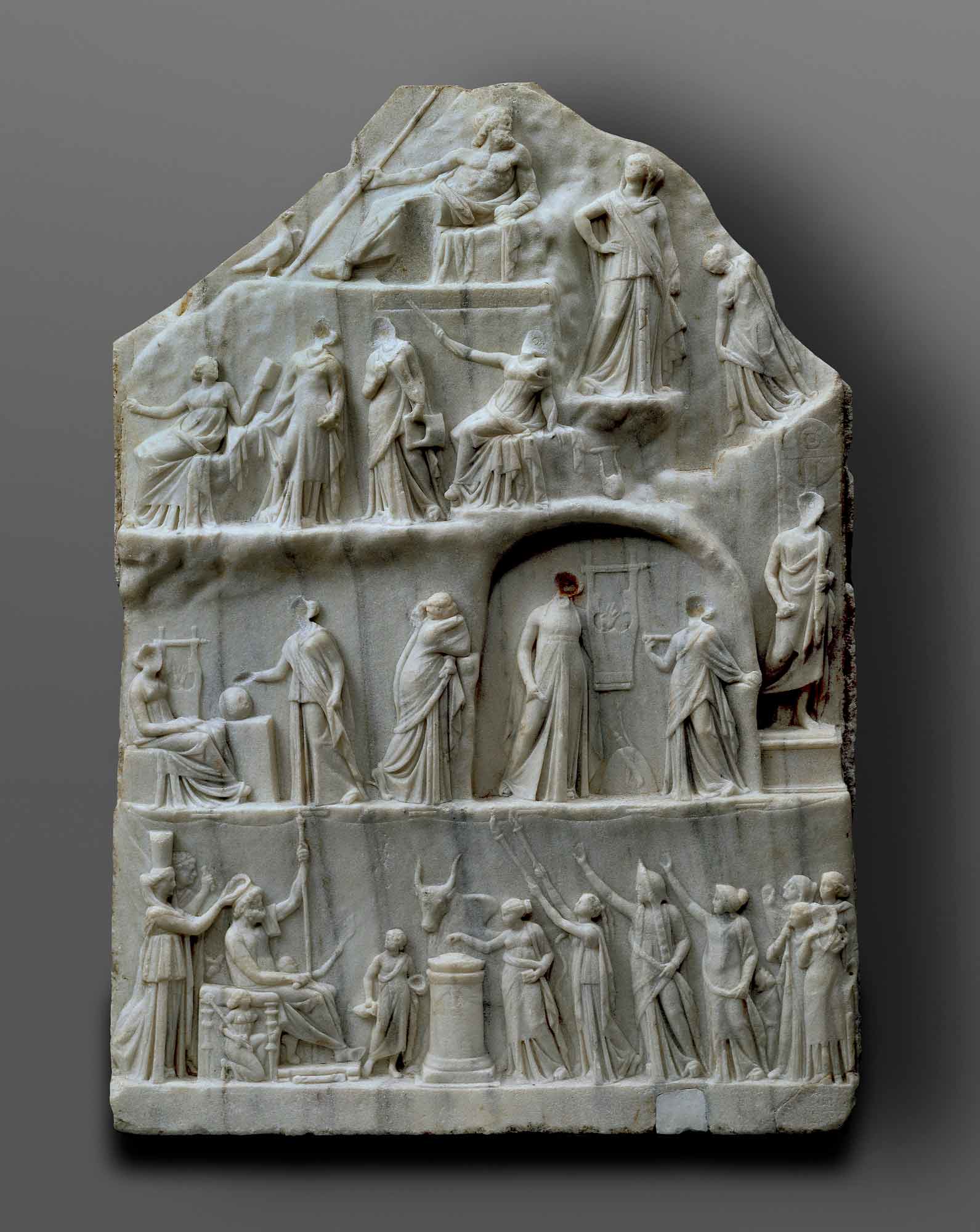 A marble block with a relief design and using a linear perspective to represent multiple figures along four rows, the top featuring a single man reclining. - click to view larger image