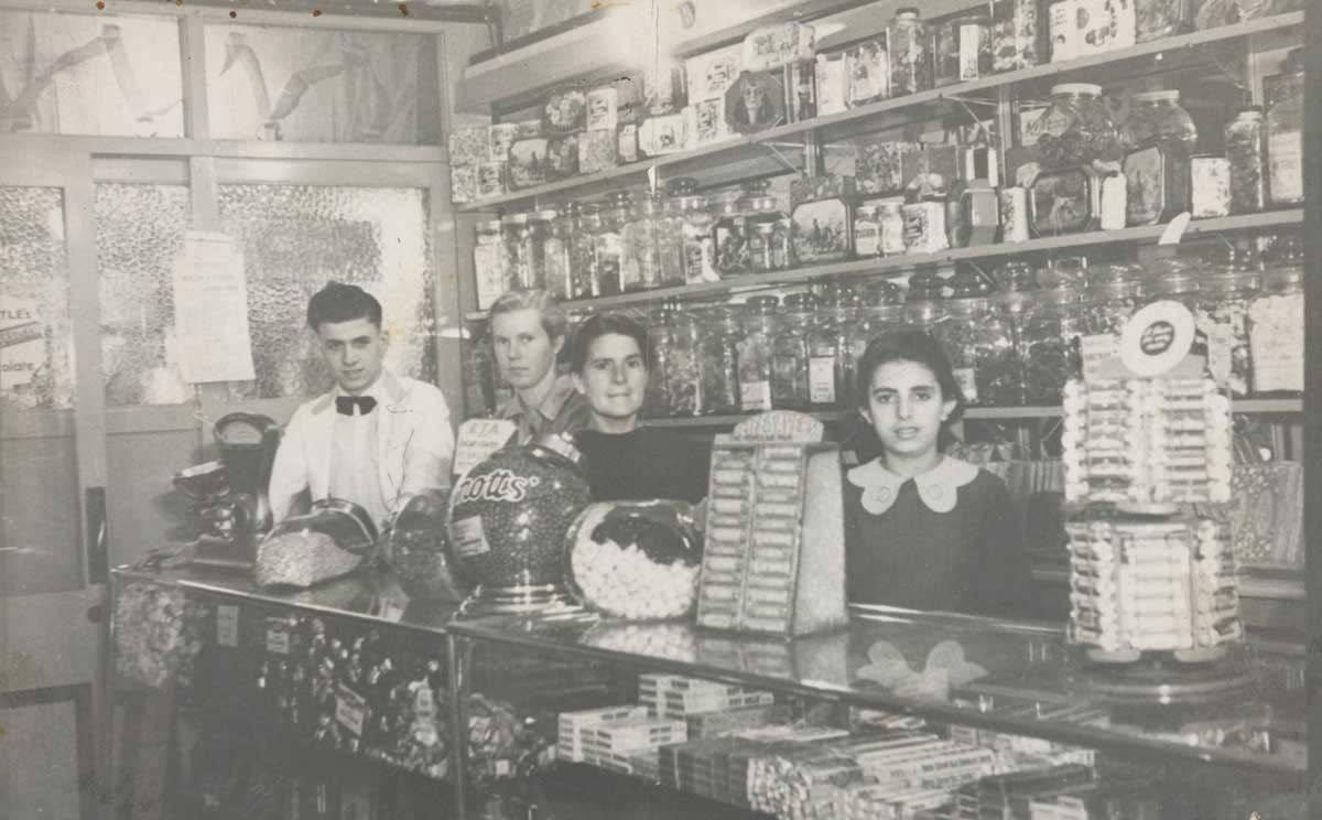 Black and white photograph of Peter, Anastasia and Anna Zantiotis with an unnamed shop assistant standing behind the counter of the Busy Bee Café