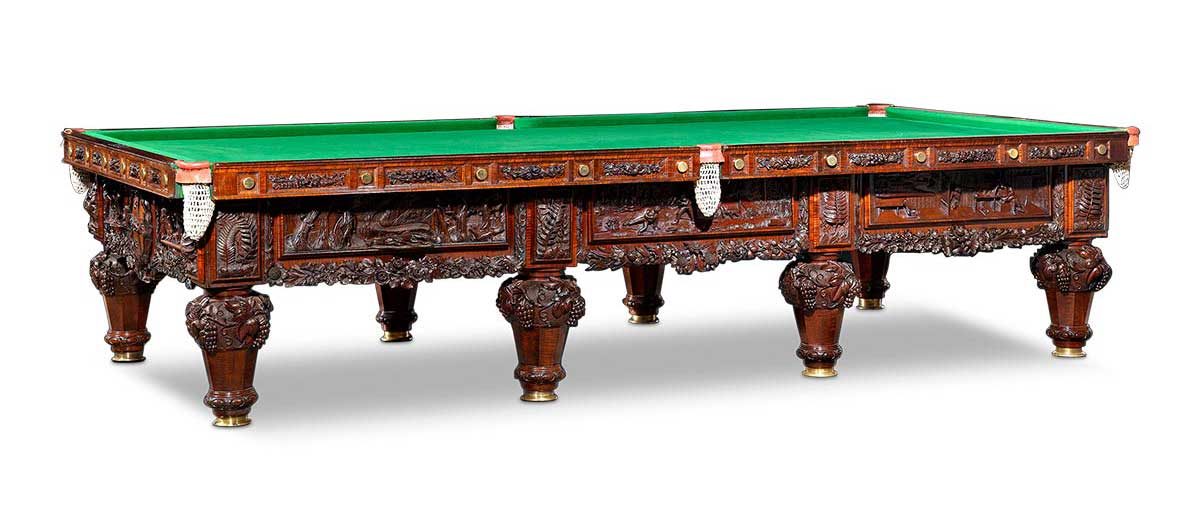 Billiard table with ornate carved designs to sides and legs.