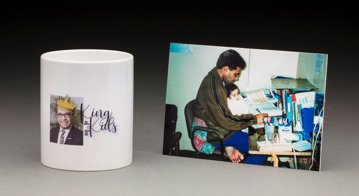 A white ceramic coffee cup with a colour portrait of a man on one side. Printed over the man's head is a yellow crown, and to the right is black text that reads 'King / of the / Kids'. A colour photograph of a man and child sits adjacent. - click to view larger image