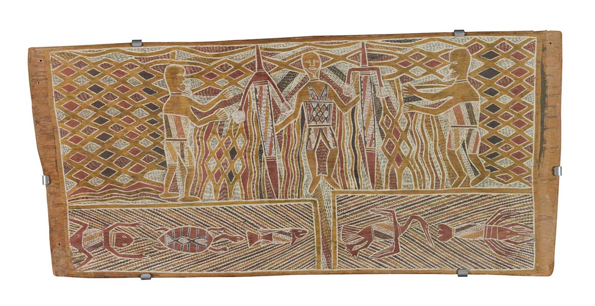 A bark painting worked with ochres on bark. It depicts a central male figure holding in each hand a pointed object decorated with feathered strings. On either side of him is another male figure. This section has a background of different coloured diamond shapes. At the foot of the painting are two crosshatched panels. The left contains a frog, a turtle and a barramundi. The one on  the right contains a diver duck and a crayfish.A bark painting worked with ochres on bark. It depicts a central male figure holding in each hand a pointed object decorated with feathered strings. On either side of him is another male figure. This section has a background of different coloured diamond shapes. At the foot of the painting are two crosshatched panels. The left contains a frog, a turtle and a barramundi. The one on  the right contains a diver duck and a crayfish. - click to view larger image