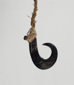 Fishhook made of a large dark purple pinna shell where strings made of various plant fibres are attached.