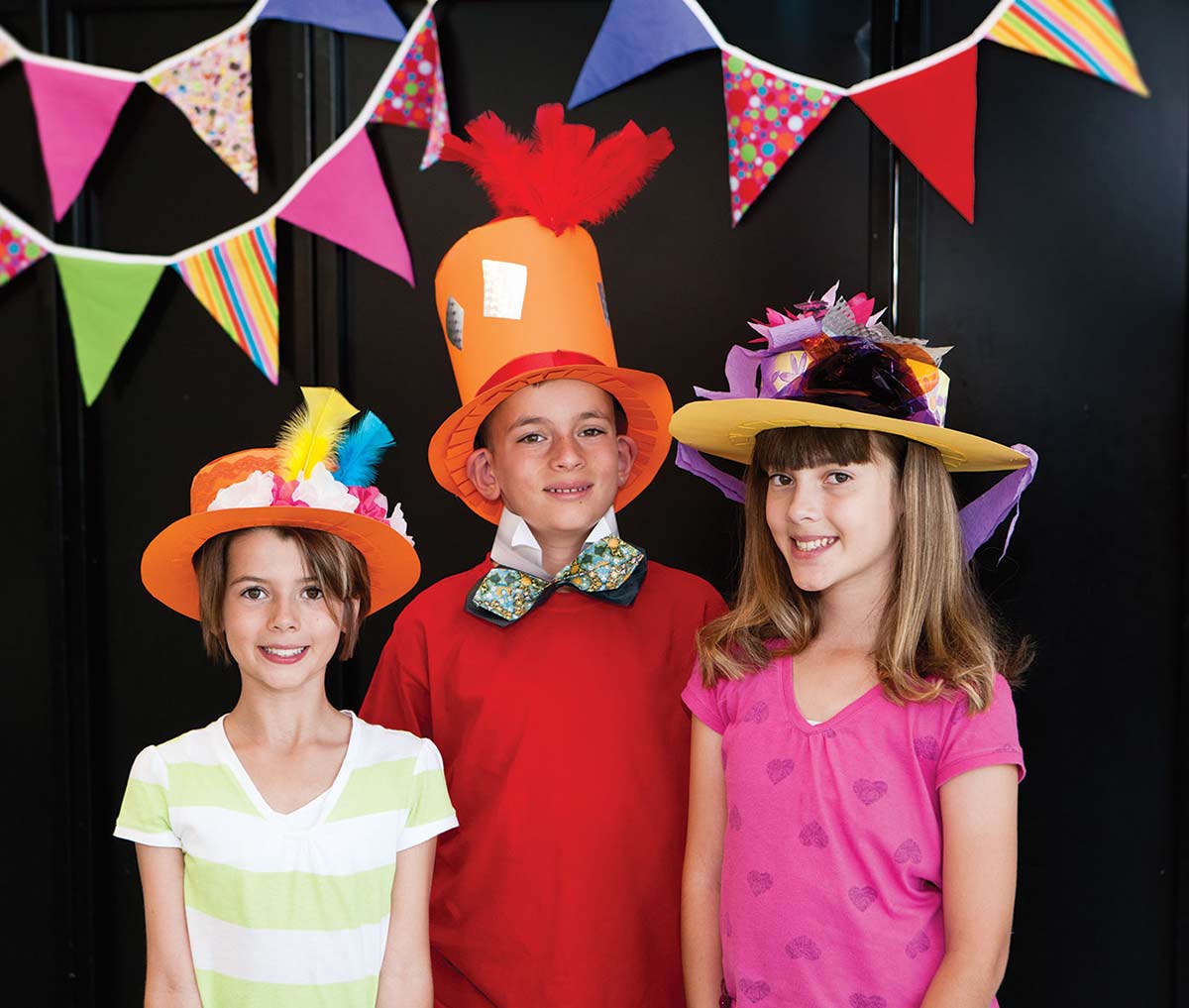 Three children dressed in colourfully decorated top hats.