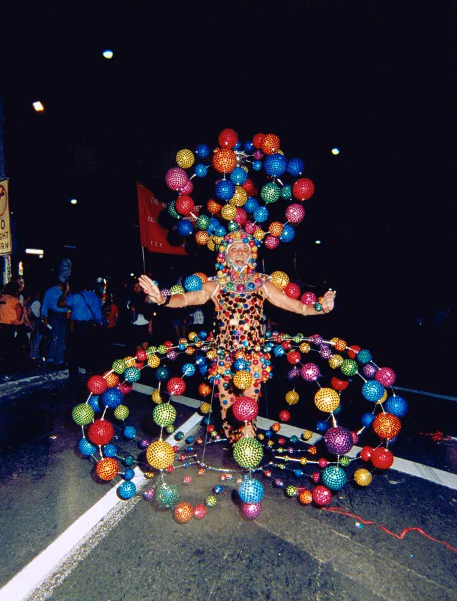 Man wearing flamboyant dress made up of colourful globes. - click to view larger image
