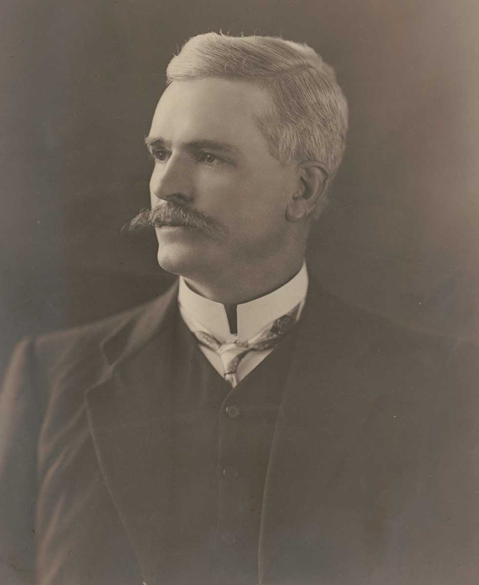 Faded, black and white studio portrait photo of silver-haired man with moustache. - click to view larger image