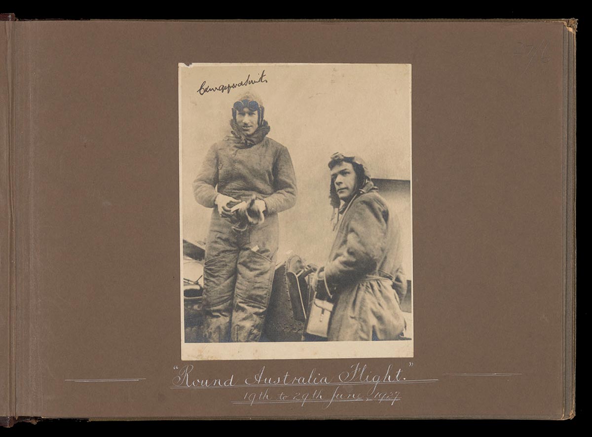 Black and white photo of Kingsford Smith and Ulm in flying clothing and helmets. - click to view larger image