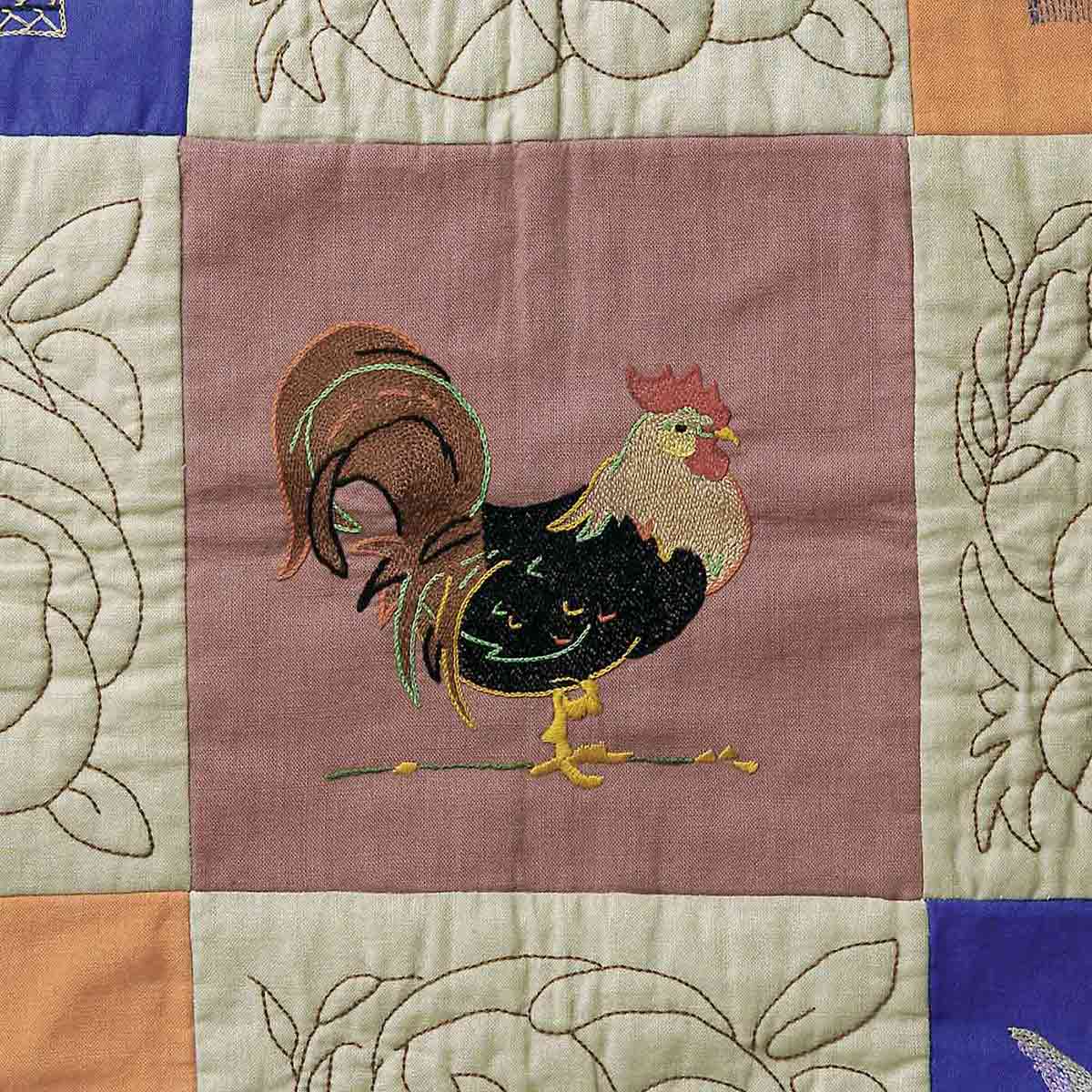 Close up quilt detail of a rooster embroidered in one of the squares. - click to view larger image