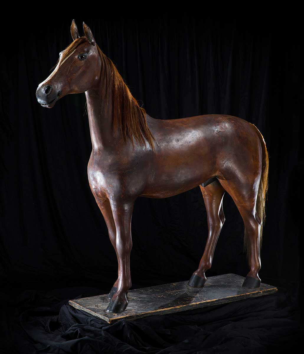 Statue of a horse mounted on a wooden board. - click to view larger image
