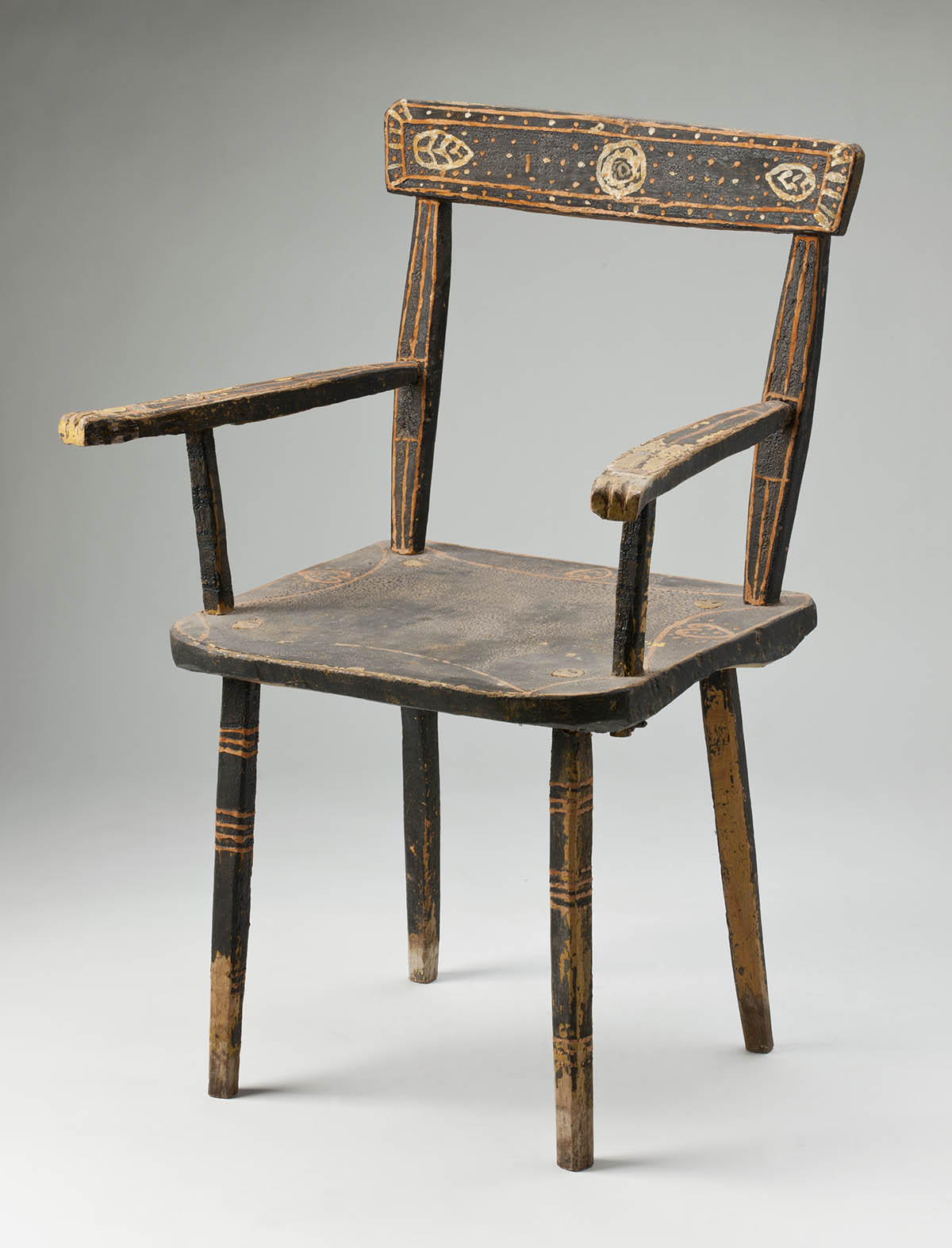 A wooden chair painted primarily in a dark brown, decorated in shades of orange and light brown on the arms, legs and back. - click to view larger image