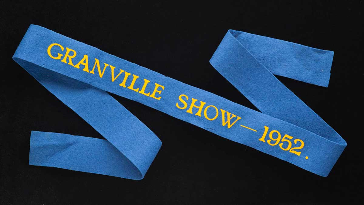 A blue prize ribbon with yellow words: Granville Show - 1952.First place ribbon won by Emilie Roach at the Granville Show, 1952. - click to view larger image