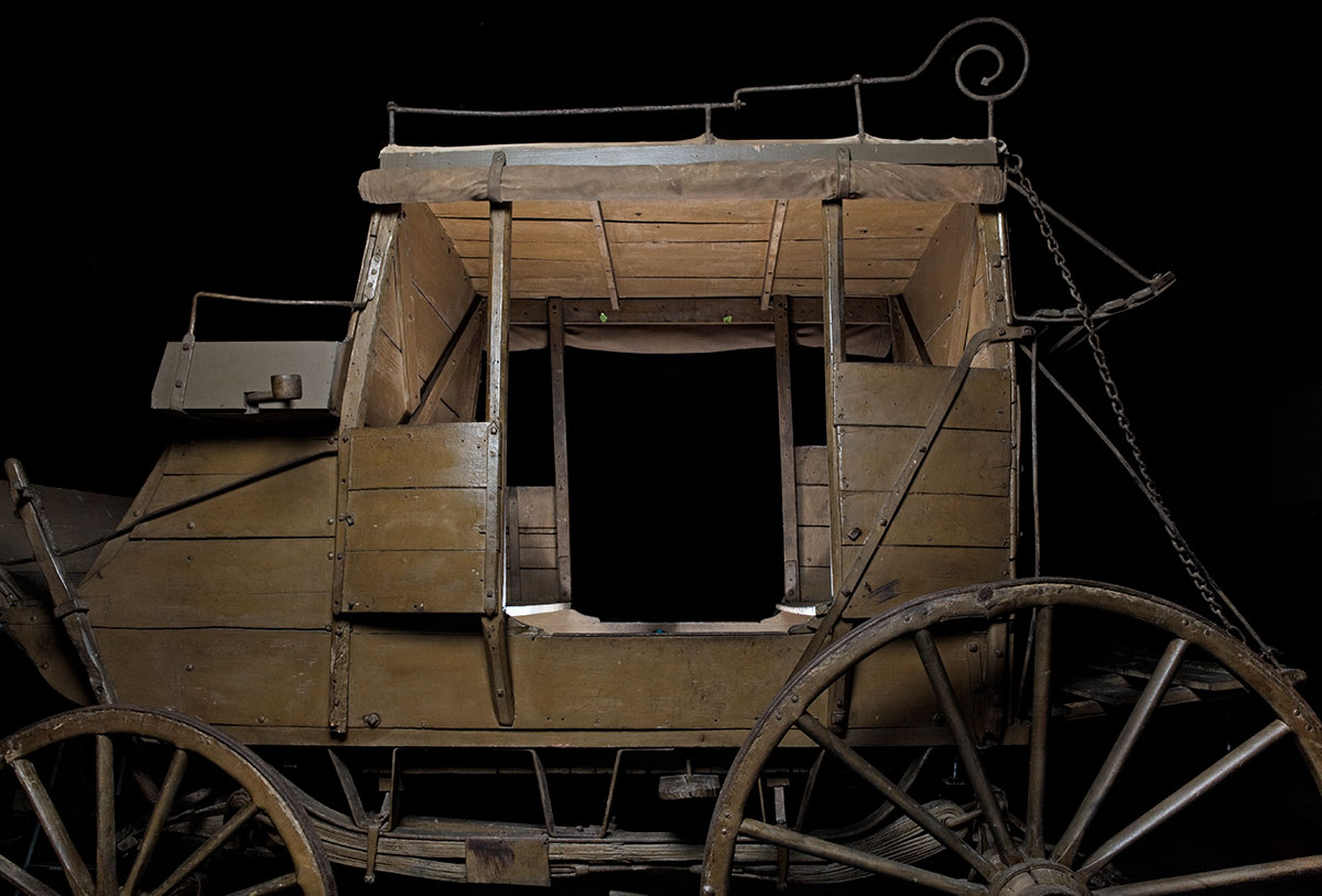 A horse-drawn, four-wheeled, eight-passenger ‘stage’ coach made from wood reinforced with iron strips and brackets. - click to view larger image