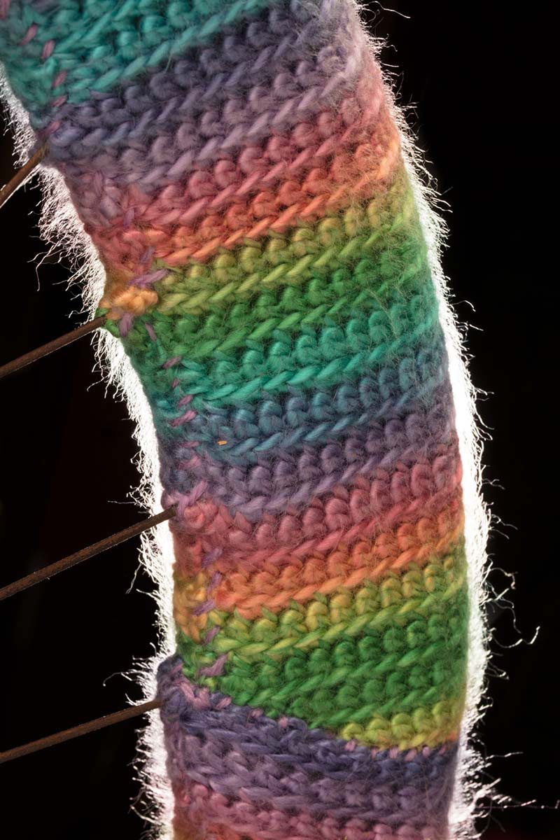 Part of a wheel covered in rainbow-coloured wool. - click to view larger image
