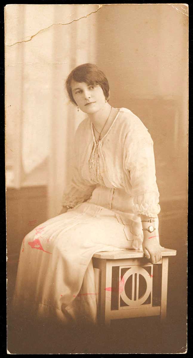 Sepia photograph portrait mounted on card that depicts Winnie O'Sullivan sitting on a stool. - click to view larger image