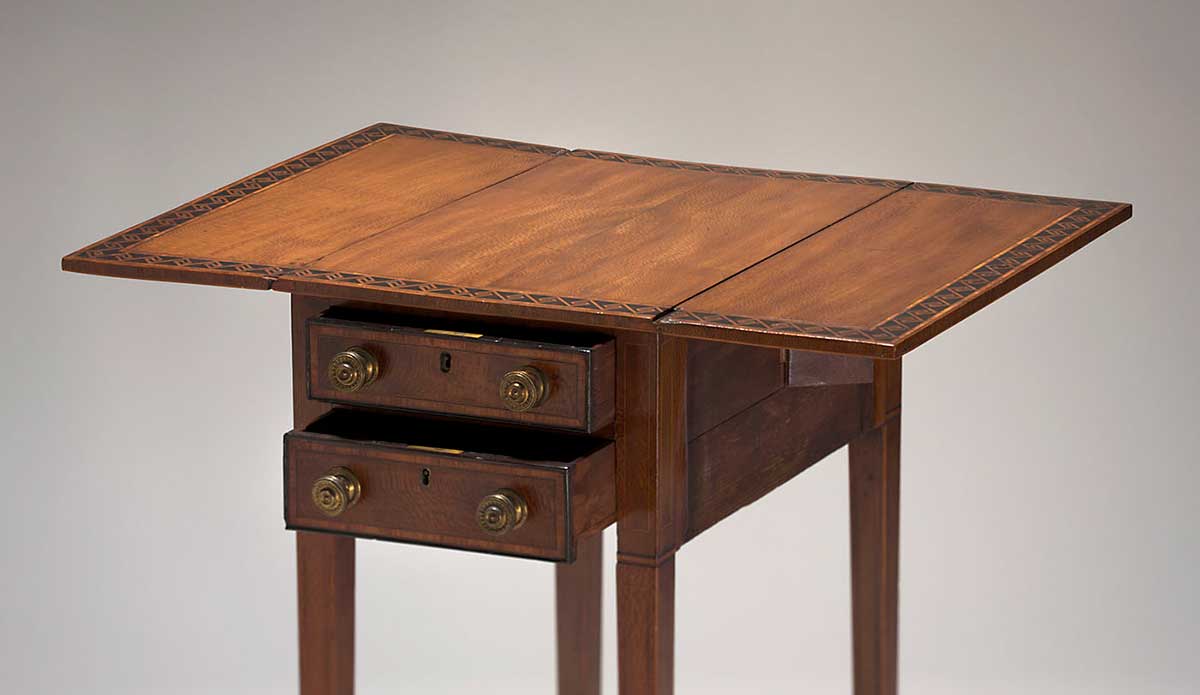 Rectangular wooden Pembroke-style table, with fold-down side leaves. The table features narrow inlaid tulipwood borders, including a wide inlaid boorder of contrasting timber in a geometric pattern on the table top.
