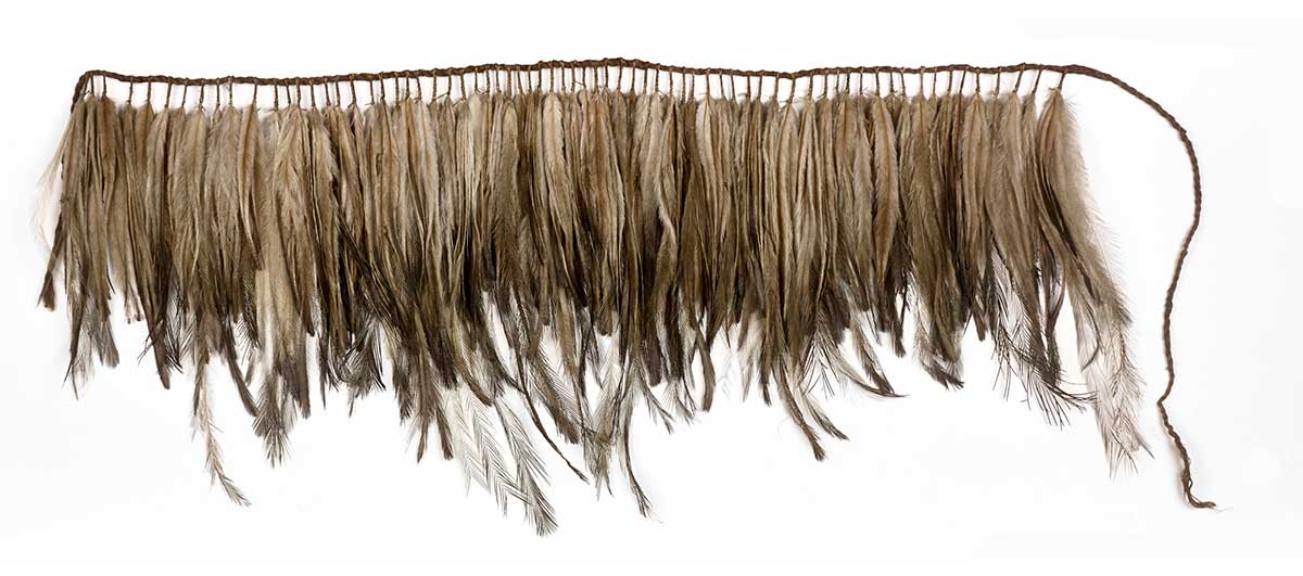 A short apron made from one hundred and twenty nine small bunches of feathers, held together at their quill ends with fibre and then wrapped around a fibre suspension cord.