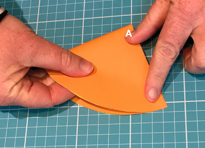 A large orange star cut out from orange paper. Two fingers point to two points on each side of the star.