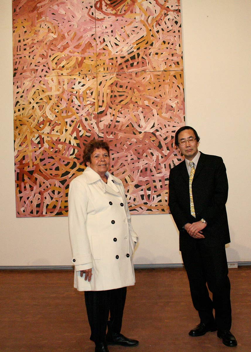 A woman and a man in formal wear standing in front of a large painting. - click to view larger image