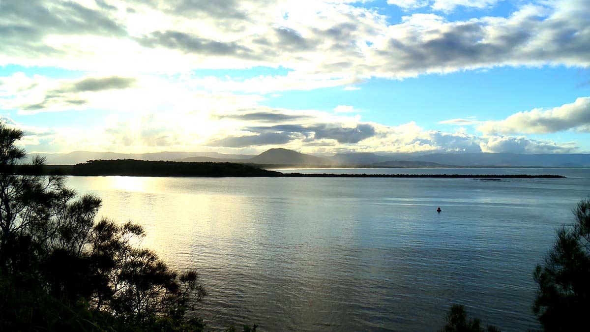 View of a large bay with a strip of land and mountainous regions in the distance.