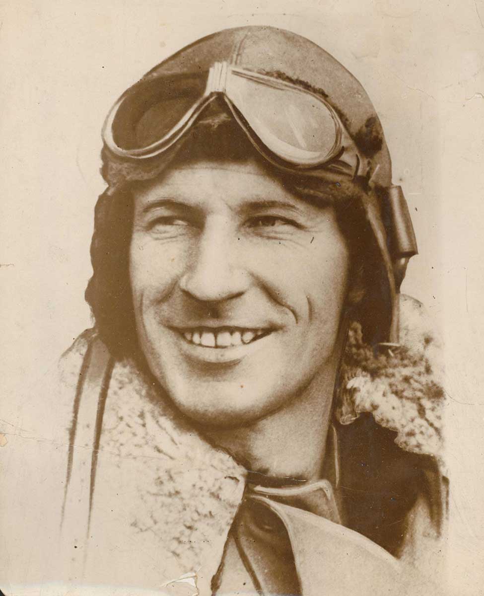 photo portrait of smiling man wearing leather helmet, goggles on forehead and thick jacket - click to view larger image
