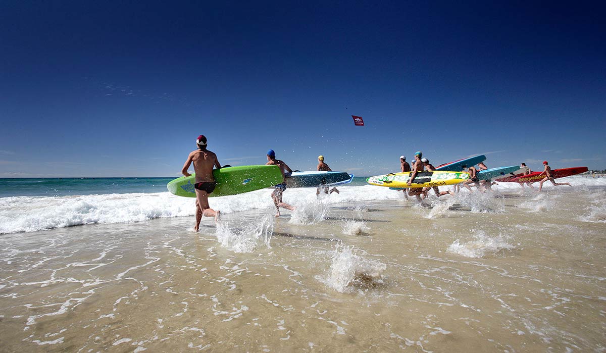 Lifesavers running into the surf with their boards at the Australian Surf Life Saving Championships, Kurrawa, Queensland, 2006.