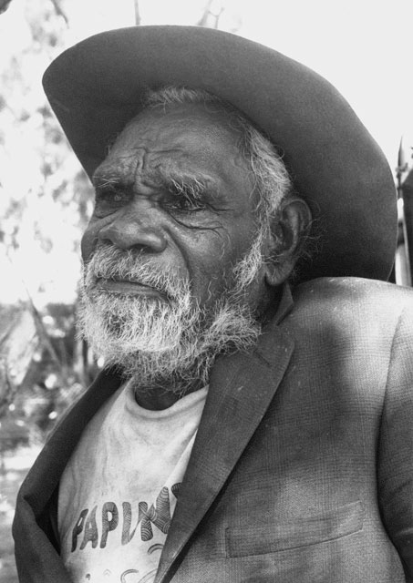 Portrait photo of an Aboriginal Australian man wearing a suit jacket and hat. - click to view larger image