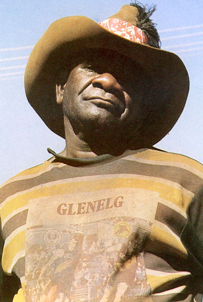 Portrait photo of an Aboriginal Australian man in a striped jumper and hat. - click to view larger image