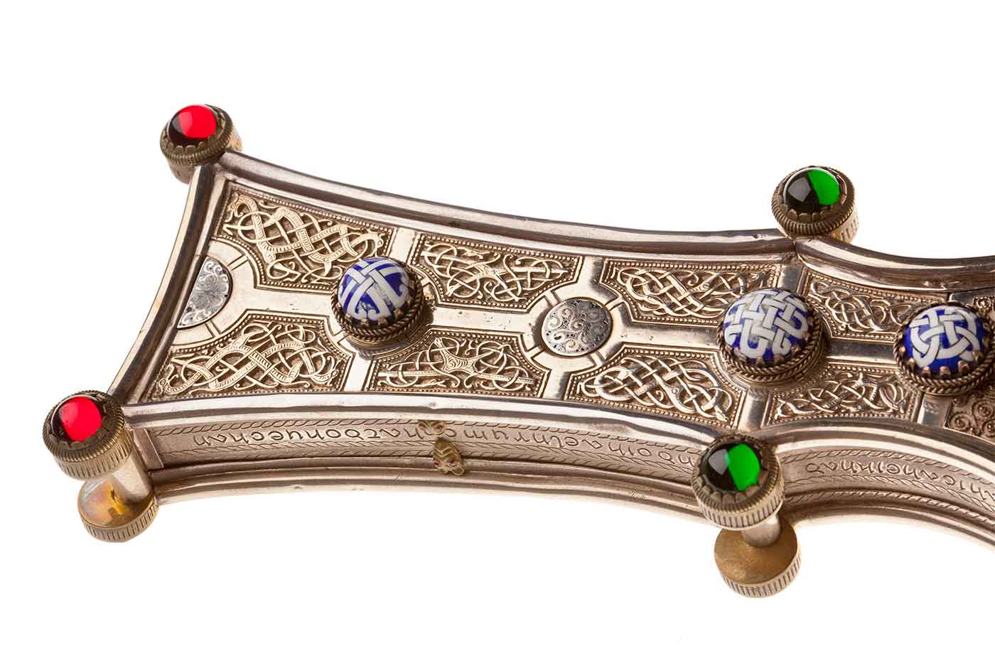 Detail of a golden cross with ornate Celtic design and gemstones. - click to view larger image