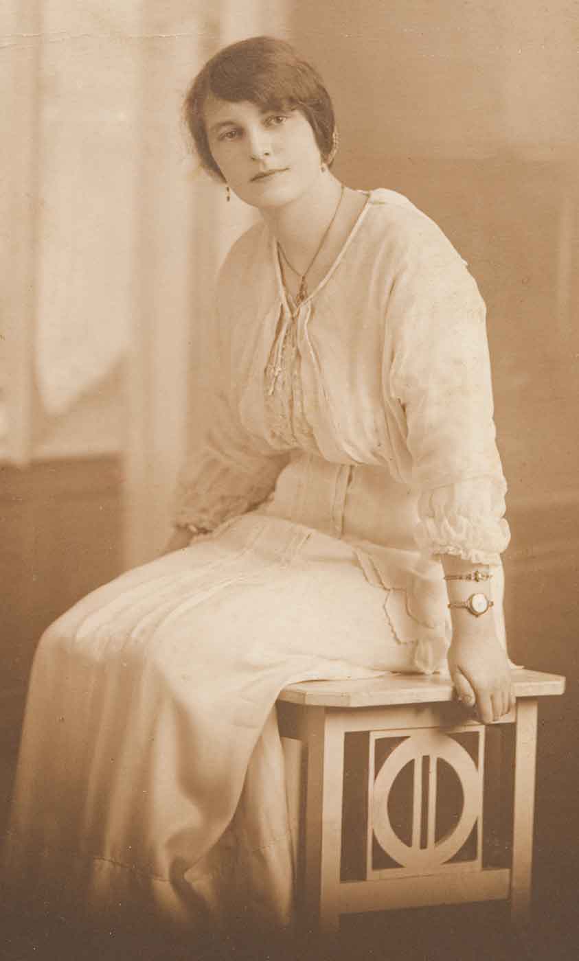 Black and white photo of a seated young woman in a white early 19th Century dress. - click to view larger image