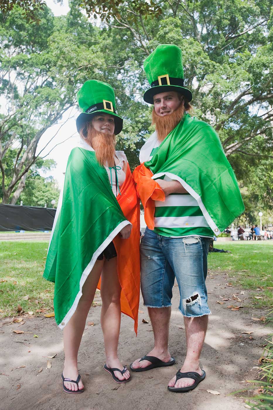 A woman and man draped in the Irish flag and wearing gimmick Irish hats pose for the camera. - click to view larger image